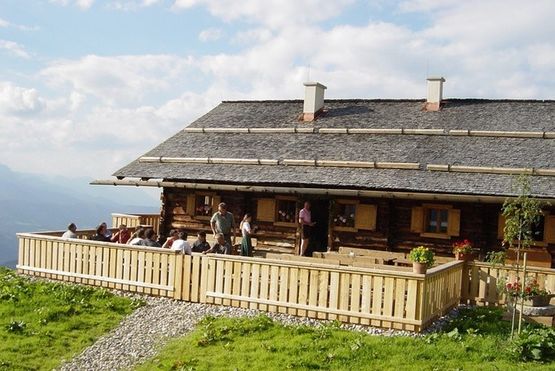 Gruppe von Menschen auf einer Terrasse von einer der Almhütten oder Jagdhütten in Salzburg